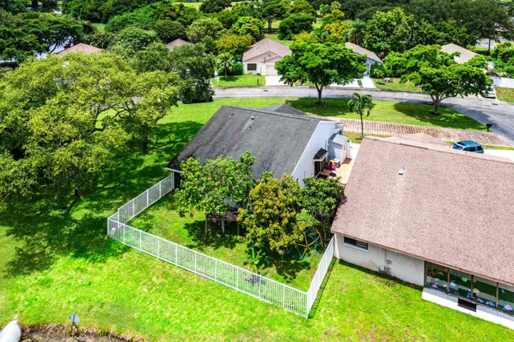 Expansive green lawn with mature trees, featuring a white fence enclosing a portion of the property