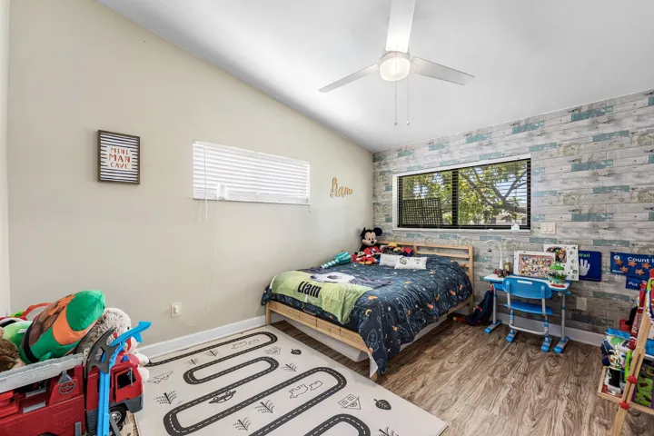 Room with wood-finish flooring, a vaulted ceiling, and a ceiling fan