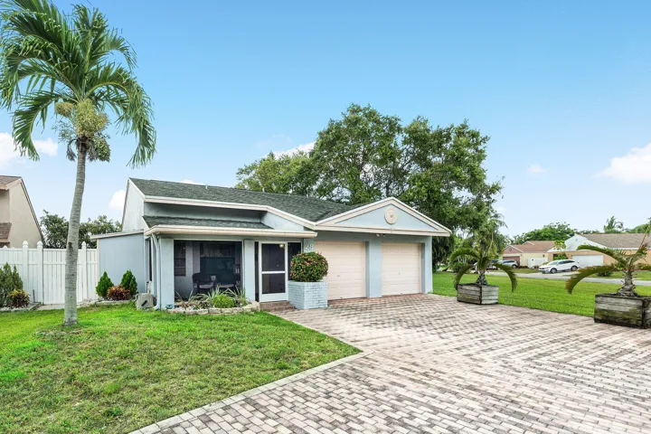 Front exterior featuring a screened porch, a two-car garage, and a paver driveway