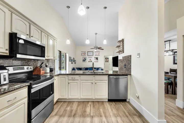 Kitchen featuring wood-finish flooring, cream cabinetry, dark stone countertops, and stainless steel appliances