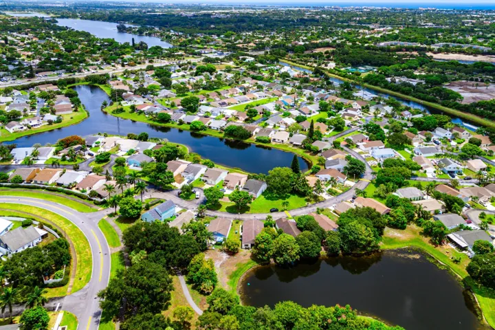 Aerial perspective of a residential community featuring numerous homes, expansive green spaces, and multiple bodies of water