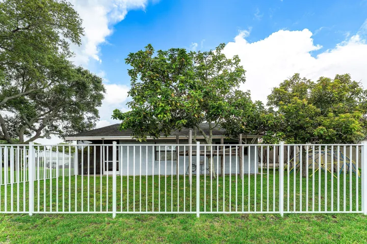 Rear exterior featuring a white metal fence enclosing a grassy yard