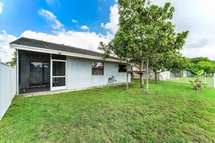 Rear exterior featuring a screened patio, sliding glass door, and a white privacy fence