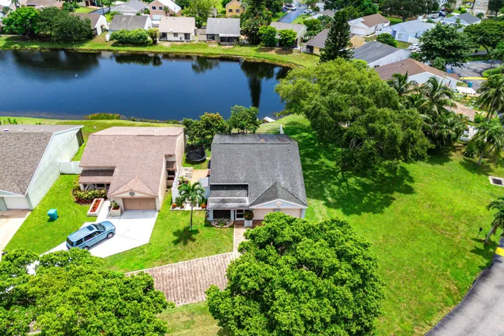 Lakeside property featuring a pitched roof, attached garage, and a concrete driveway