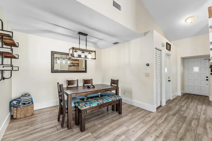 Open-concept area featuring wood-finish flooring, a decorative front entry door, and a built-in wall shelf unit