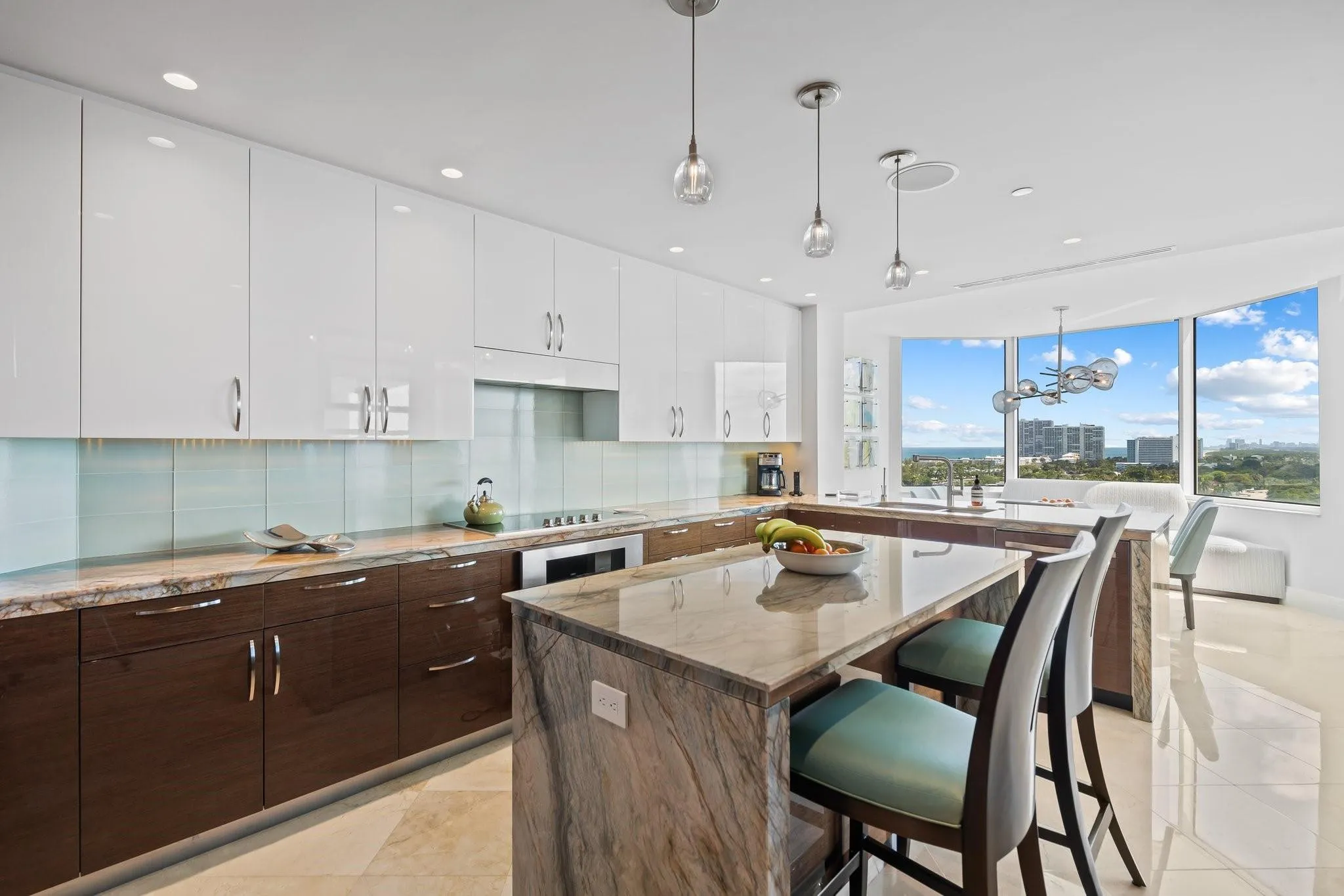 Spacious kitchen featuring an expansive island with a stone countertop, two-tone cabinetry with upper white gloss and lower wood-finish, a light blue tile backsplash, and recessed lighting