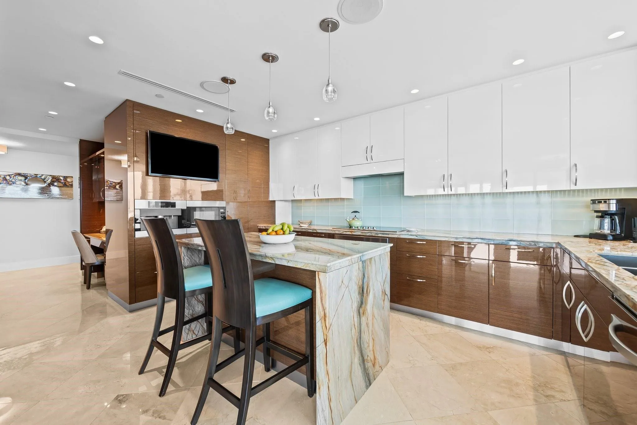 Gourmet kitchen featuring a waterfall island with stone countertop, contrasting high-gloss white and wood-finish cabinetry, a tiled backsplash, and recessed lighting