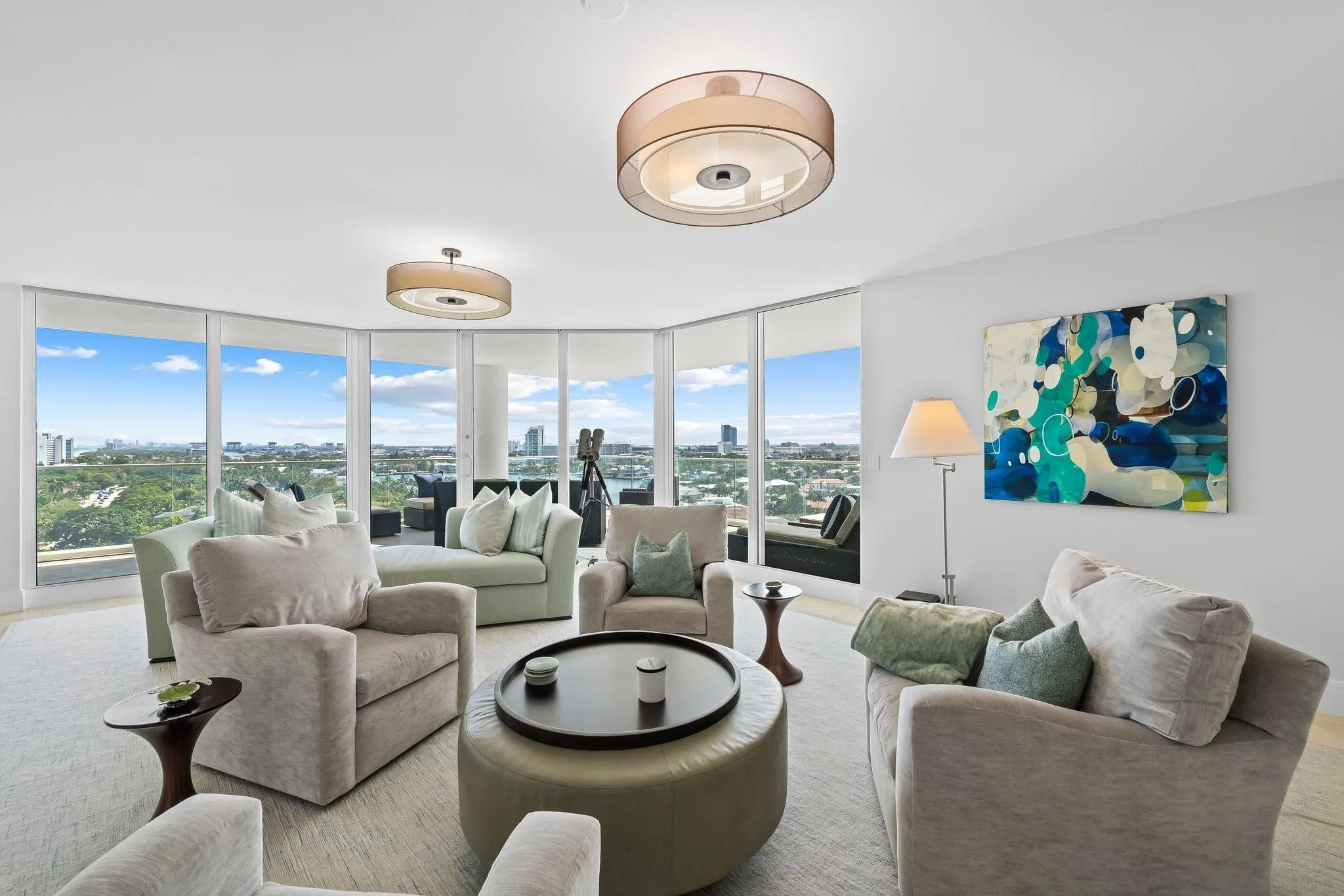 Spacious living area featuring floor-to-ceiling windows, panoramic urban and greenbelt scenery, recessed lighting, and elegant wood-finish flooring