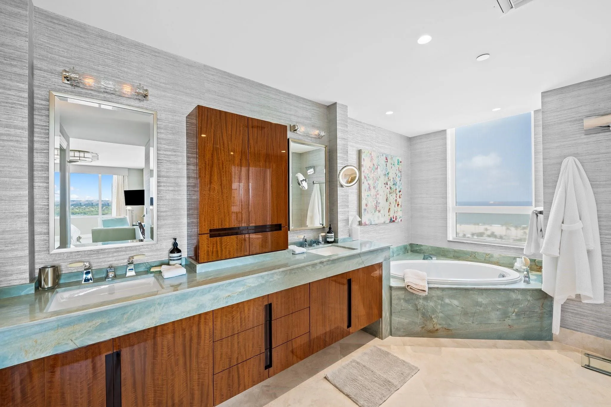Bathroom featuring a built-in soaking tub, wood-finish vanity with dual integrated sinks, and floor-to-ceiling window