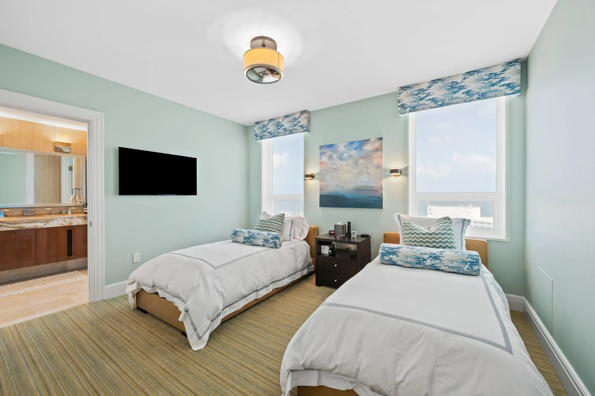 Room featuring two windows with patterned valances, a mounted television, a ceiling light fixture, and horizontal wood-finish flooring