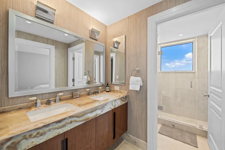 Dual vanity with a stone countertop, featuring two integrated rectangular sinks and wall-mounted faucets