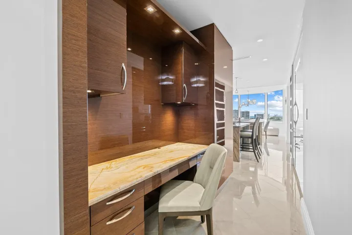 Built-in wood-finish cabinetry and desk with stone countertop