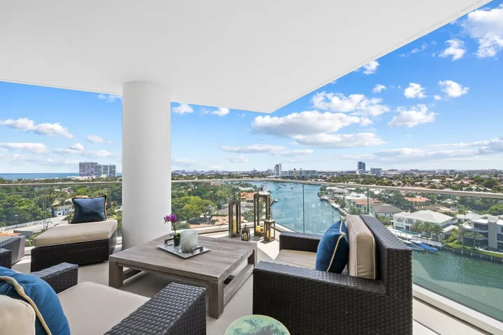 Expansive balcony featuring a glass railing, offering panoramic waterscape and cityscape views