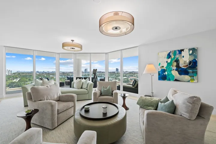 Spacious living area featuring floor-to-ceiling windows, panoramic urban and greenbelt scenery, recessed lighting, and elegant wood-finish flooring