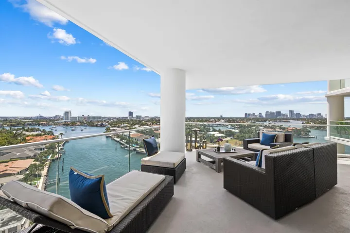 Expansive outdoor terrace featuring a glass railing, smooth concrete flooring, and a wide-open overhead ceiling