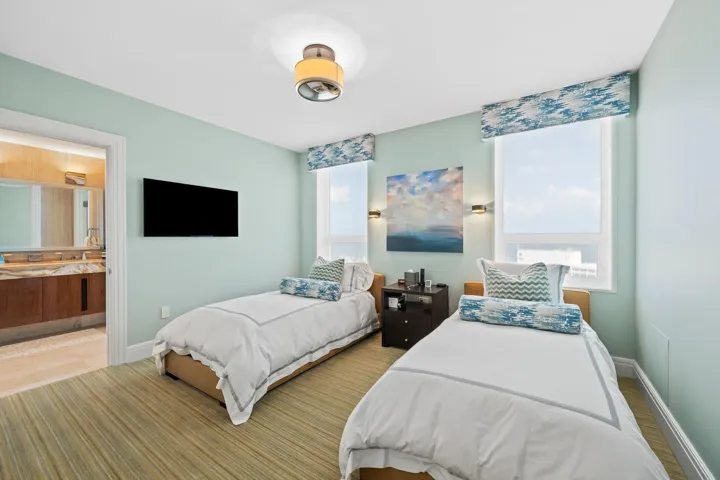Room featuring two windows with patterned valances, a mounted television, a ceiling light fixture, and horizontal wood-finish flooring