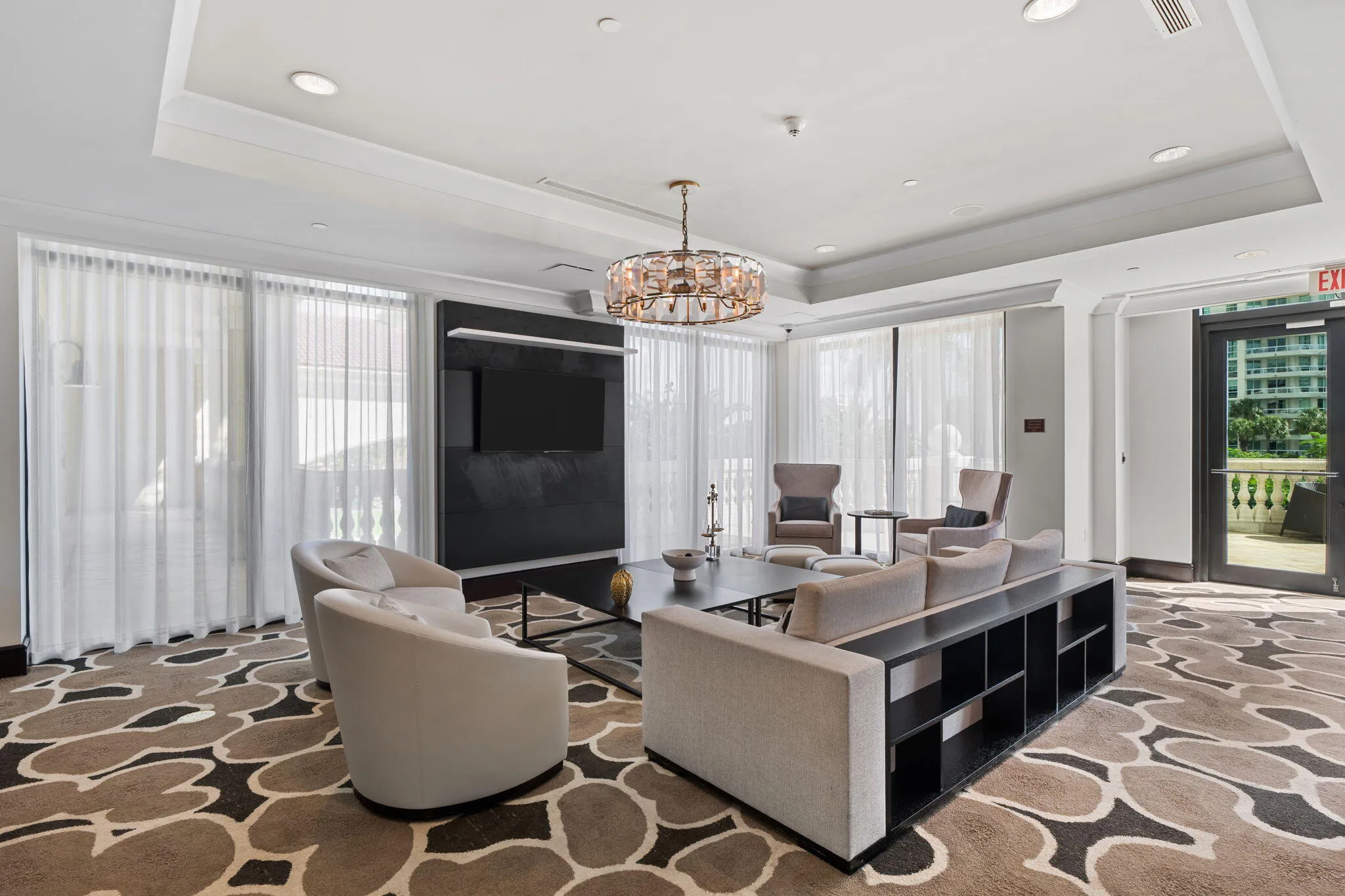 Alternate view of the club room lounge, featuring a large gathering space, television & terrace access.