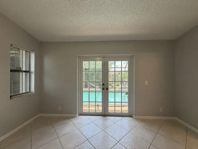 PRIMARY BEDROOM WITH FRENCH DOORS OPENING TO SCREENED POOL