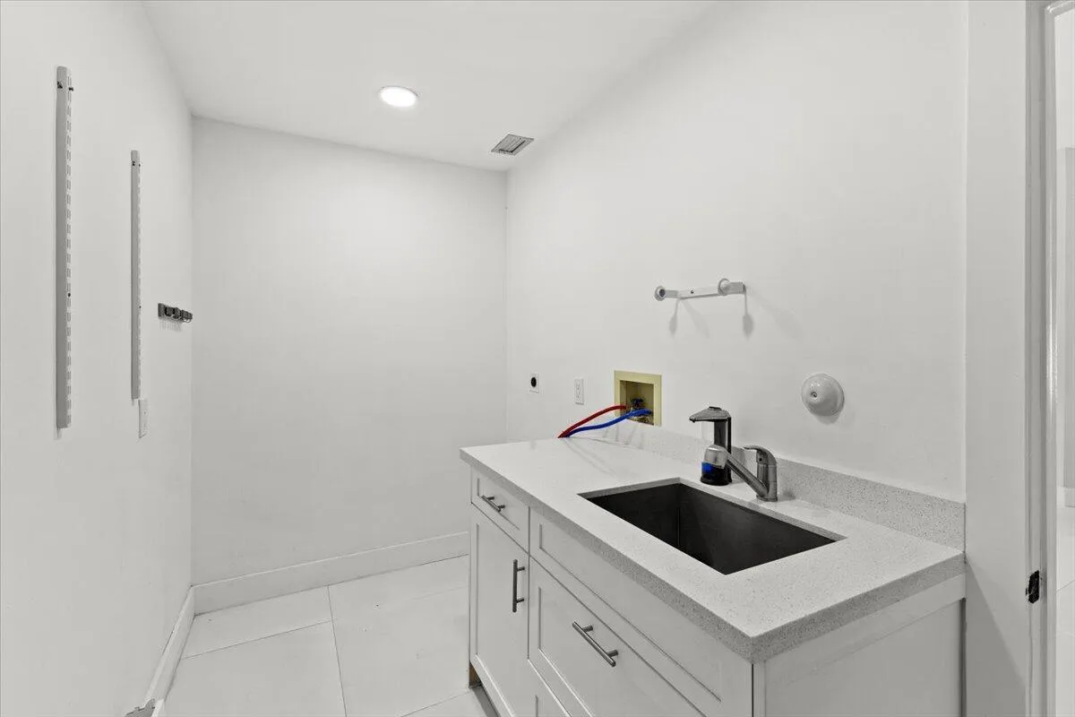Laundry room featuring washer and dryer hookups, a utility sink, and convenient under sink drawer storage.