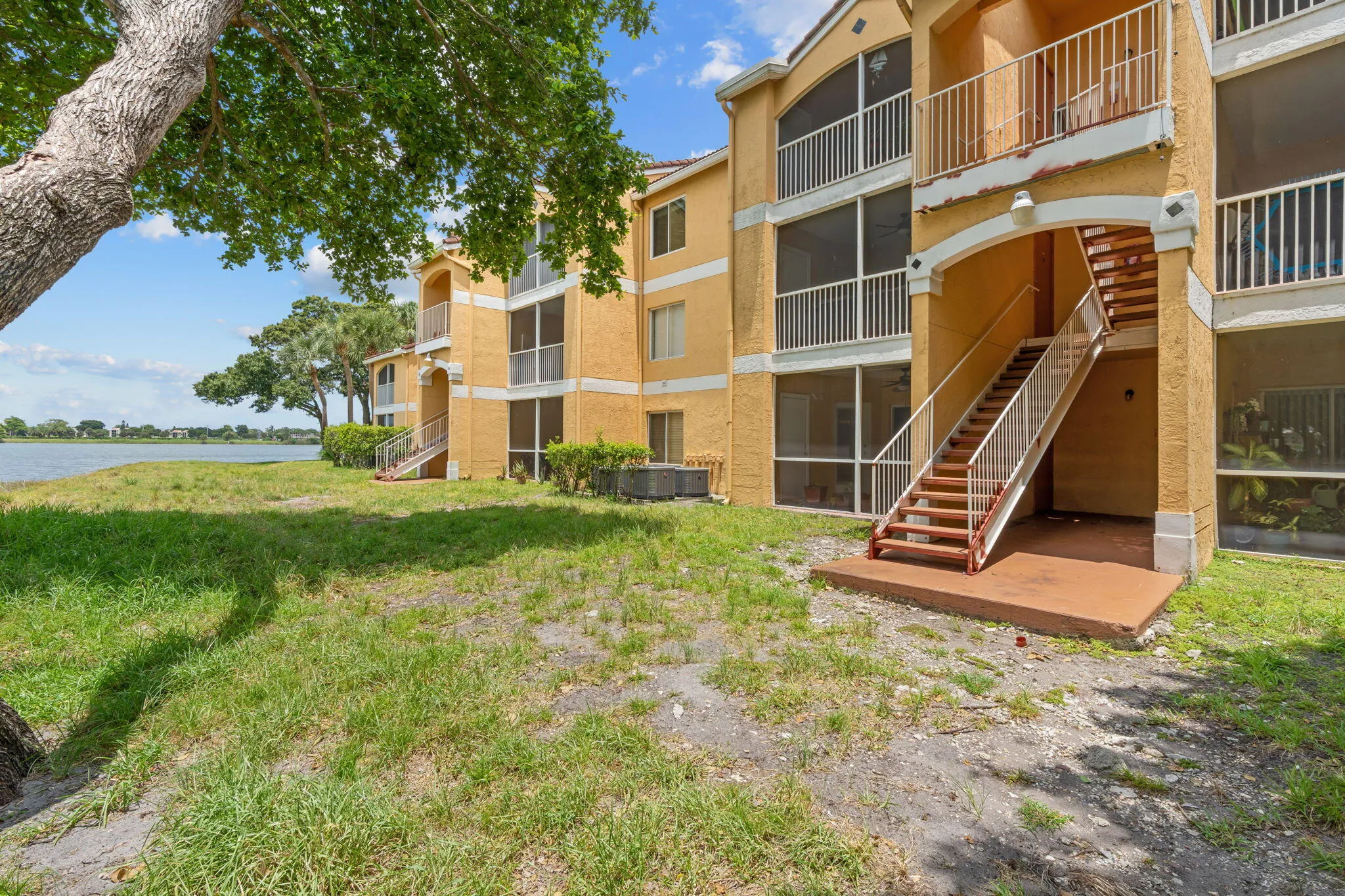 Rear exterior highlights screened patios and balconies with direct access to open green space and the community lake.