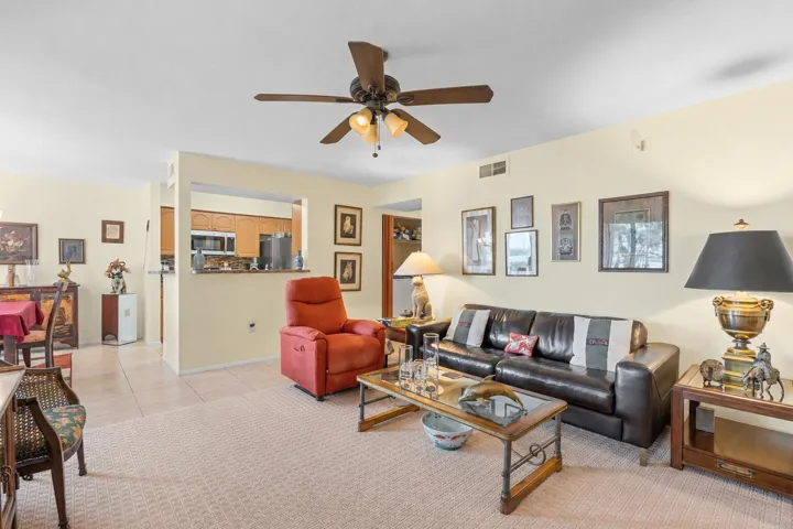 Bright living room centered around large windows that bring in natural light and create an open connection to the kitchen and dining area.