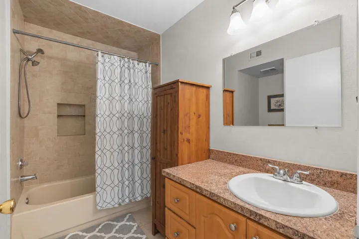 Primary bathroom features an extended vanity with generous counter space and a tub-shower combination with tile surround.