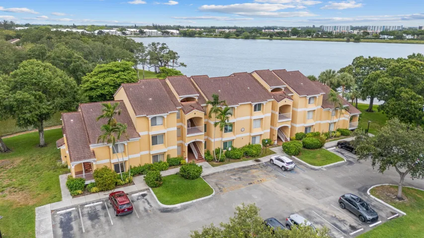 Aerial view showcases the building’s lakeside location within a well-maintained community surrounded by mature landscaping.