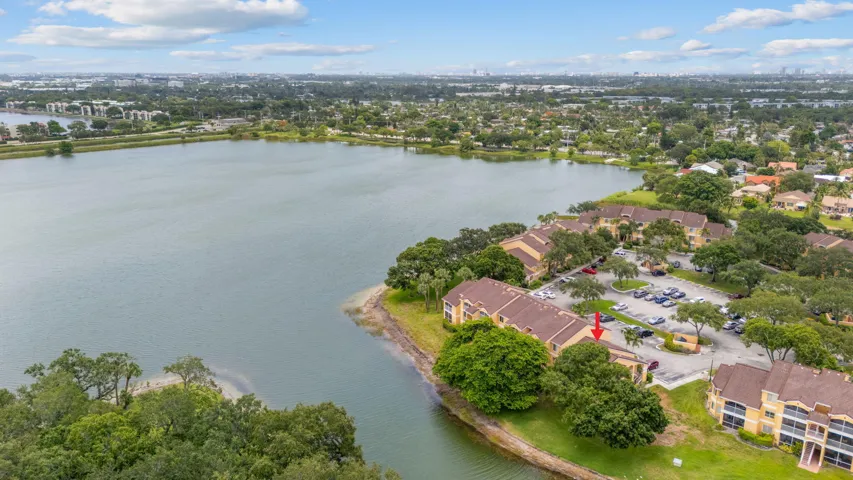 Aerial view captures the building’s waterfront setting along a peaceful lake with abundant green space nearby.