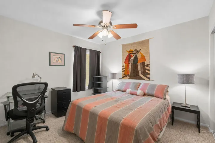 Secondary bedroom with carpet flooring, ceiling fan, and a window that fills the room with natural light.