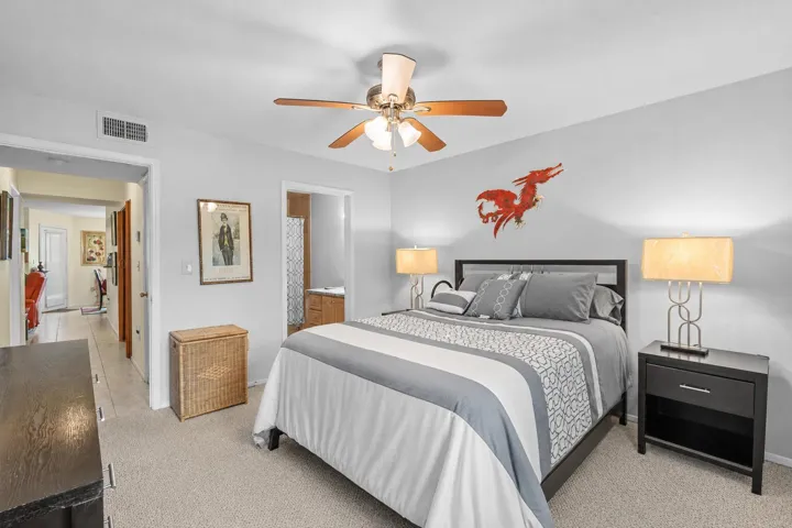 Primary bedroom offers a comfortable layout with carpet flooring, ceiling fan, and direct access to the en-suite bath.