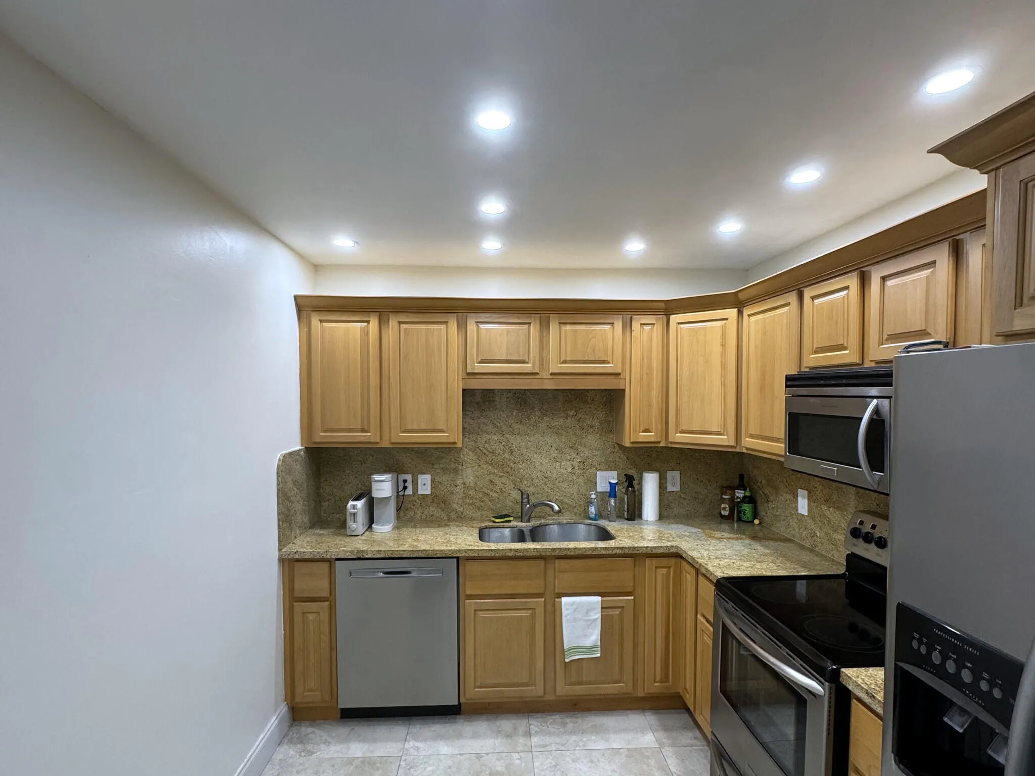 Kitchen featuring warm-toned wood cabinetry, stone countertops, and a full stone backsplash