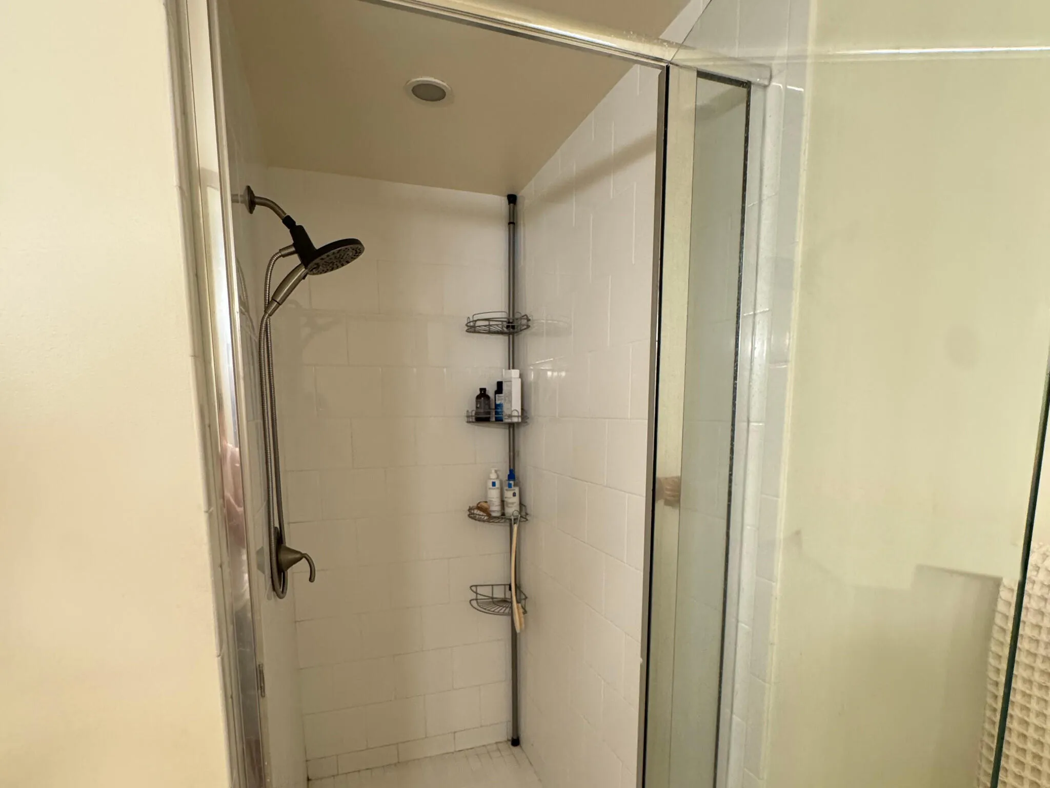 Shower enclosure with white subway tile, a recessed ceiling light, and a brushed nickel shower fixture