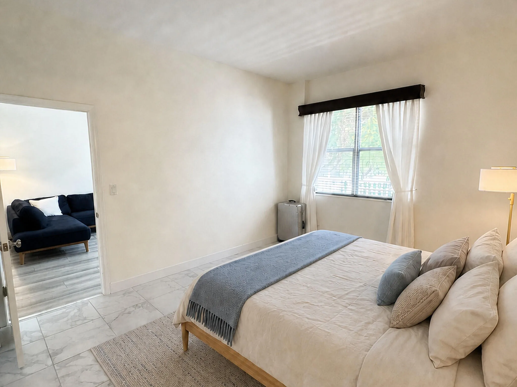 Bedroom featuring tile flooring, neutral wall tones, and a window with blinds and drapes