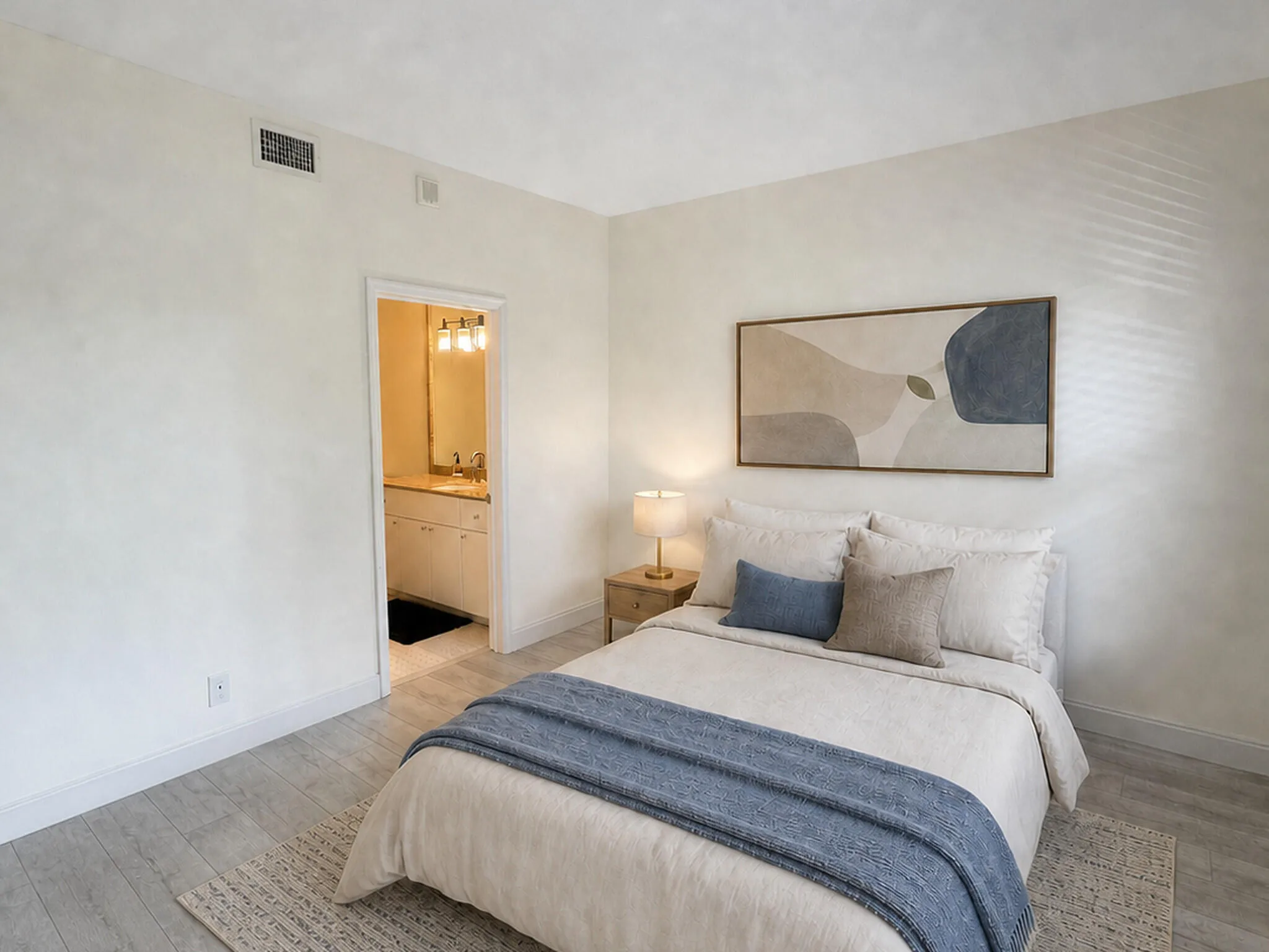 Bedroom featuring light wood-finish flooring and a doorway to a bathroom