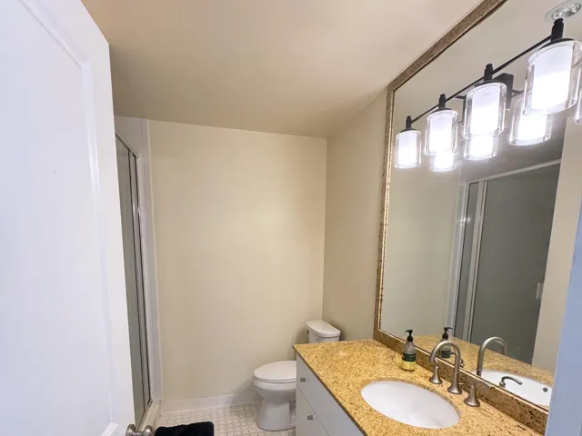 Bathroom featuring a vanity with a golden-toned countertop, an oval undermount sink, and a framed mirror