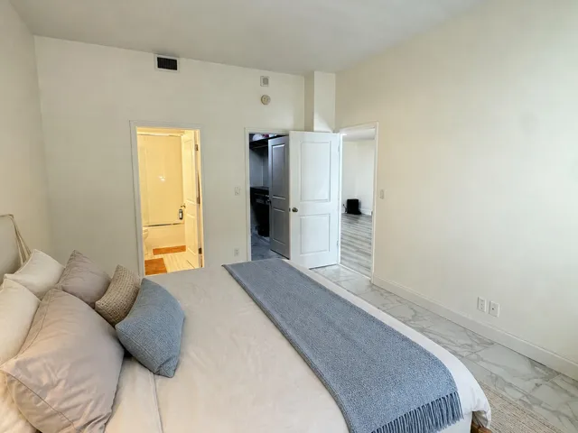 Bedroom featuring marble-finish flooring, crisp white walls, and a recessed ceiling vent