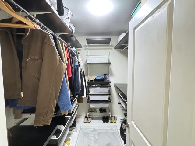 Walk-in closet featuring adjustable shelving, integrated drawers, hanging rods, recessed lighting, and a paneled door