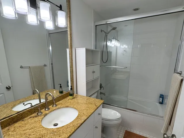 Bathroom featuring a vanity with a golden-toned countertop, dual sinks, and brushed nickel faucets