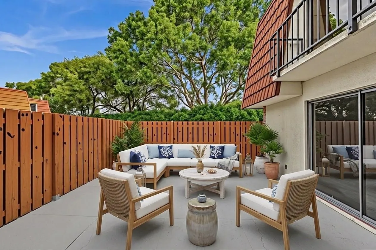 Expansive outdoor patio featuring a concrete surface, privacy fencing, and direct access to interior spaces via sliding glass doors