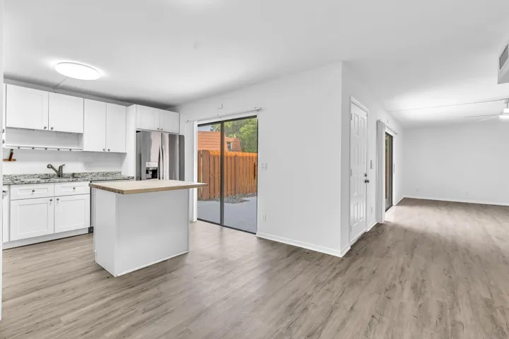 Modern kitchen with white cabinetry and granite countertops, featuring an island with a wood-finish top
