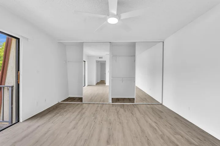 Room featuring wood-finish flooring, white walls, and a ceiling fan with integrated lighting