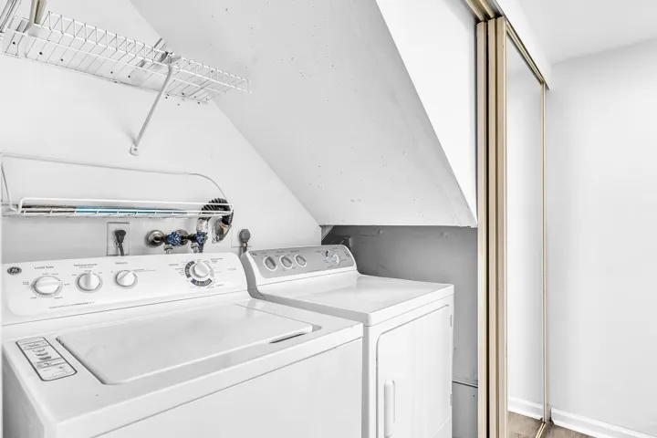Dedicated laundry area featuring a top-load washing machine, front-load dryer, and wall-mounted wire shelving