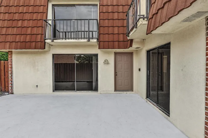 Exterior facade featuring a concrete patio, tile roofing, and multiple sliding glass doors