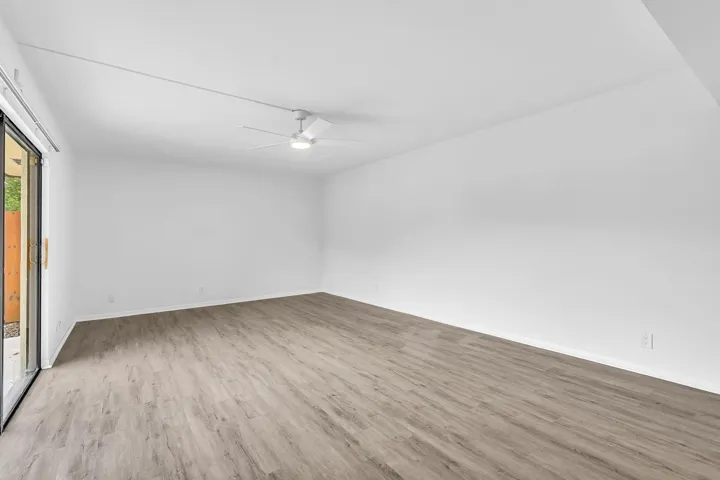 Spacious room featuring wood-finish flooring, white walls, and a contemporary ceiling fan with integrated lighting