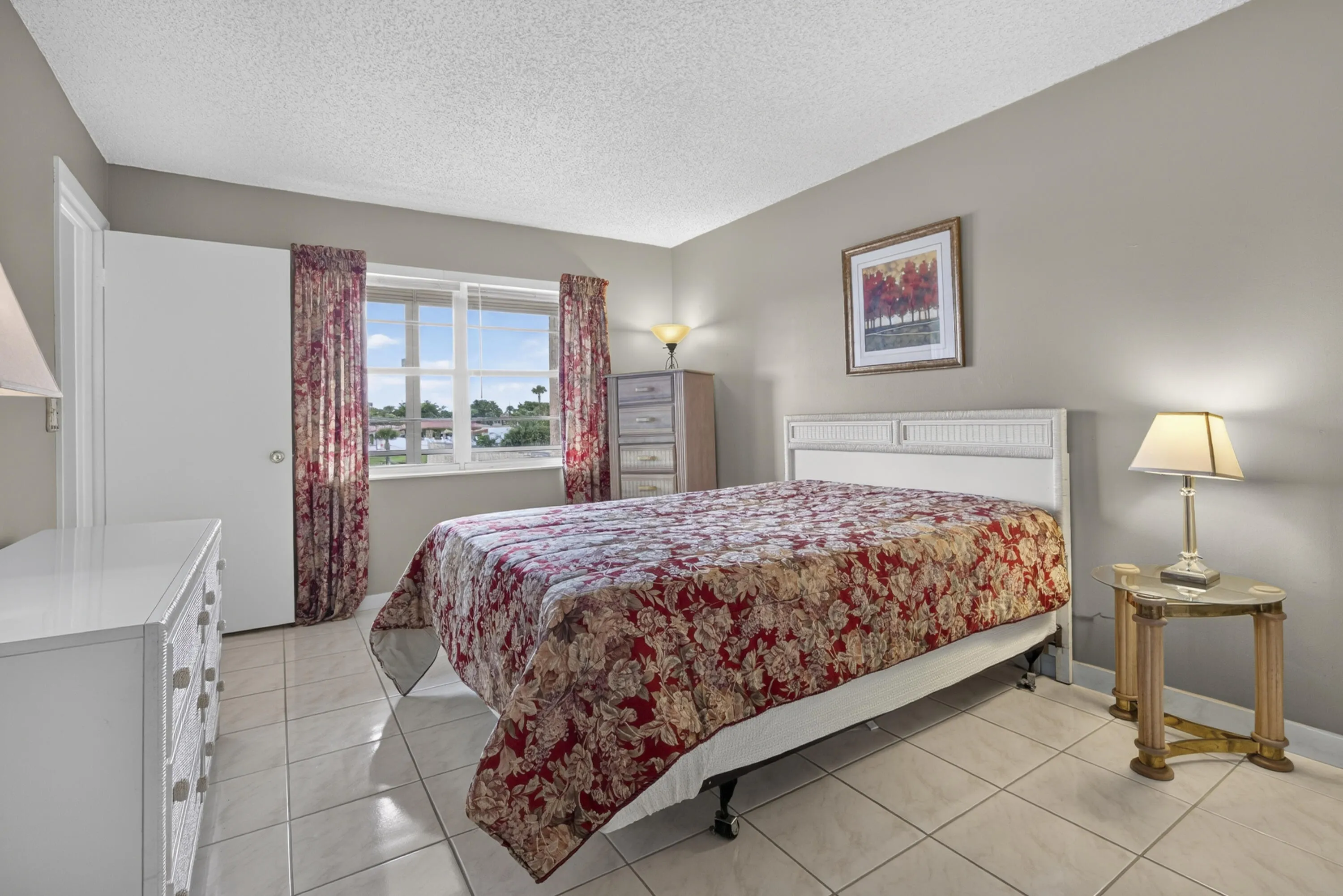 Bright room featuring a multi-pane window with a water view, neutral wall color, white ceiling, and tiled flooring