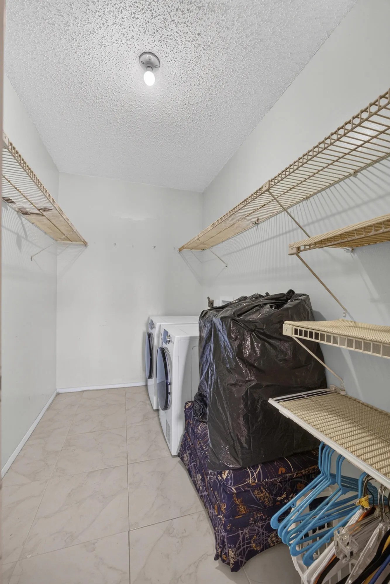 Laundry area with tile flooring and multiple wire shelving units