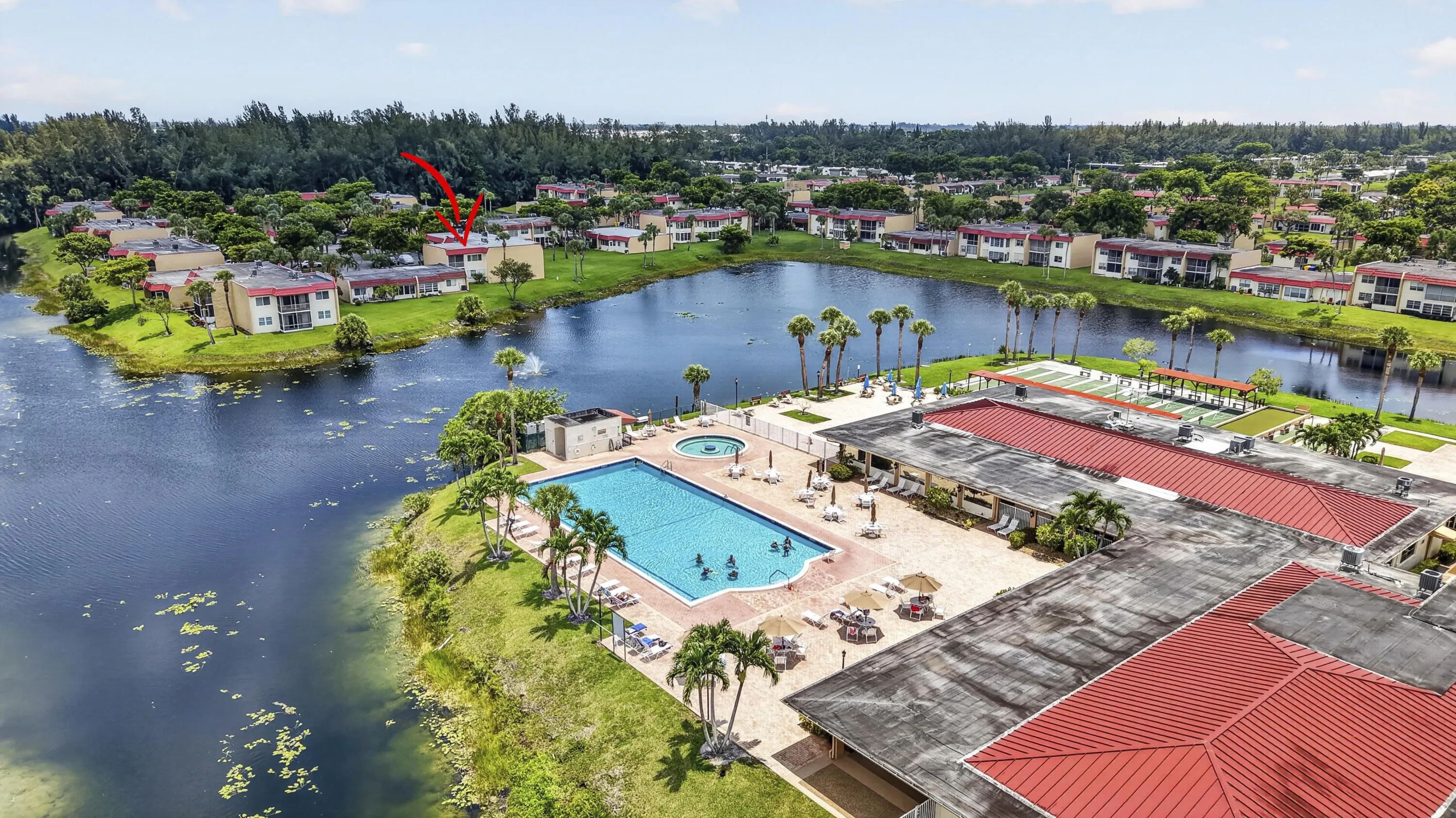 Community pool area with a large swimming pool, surrounding patio, and shuffleboard courts