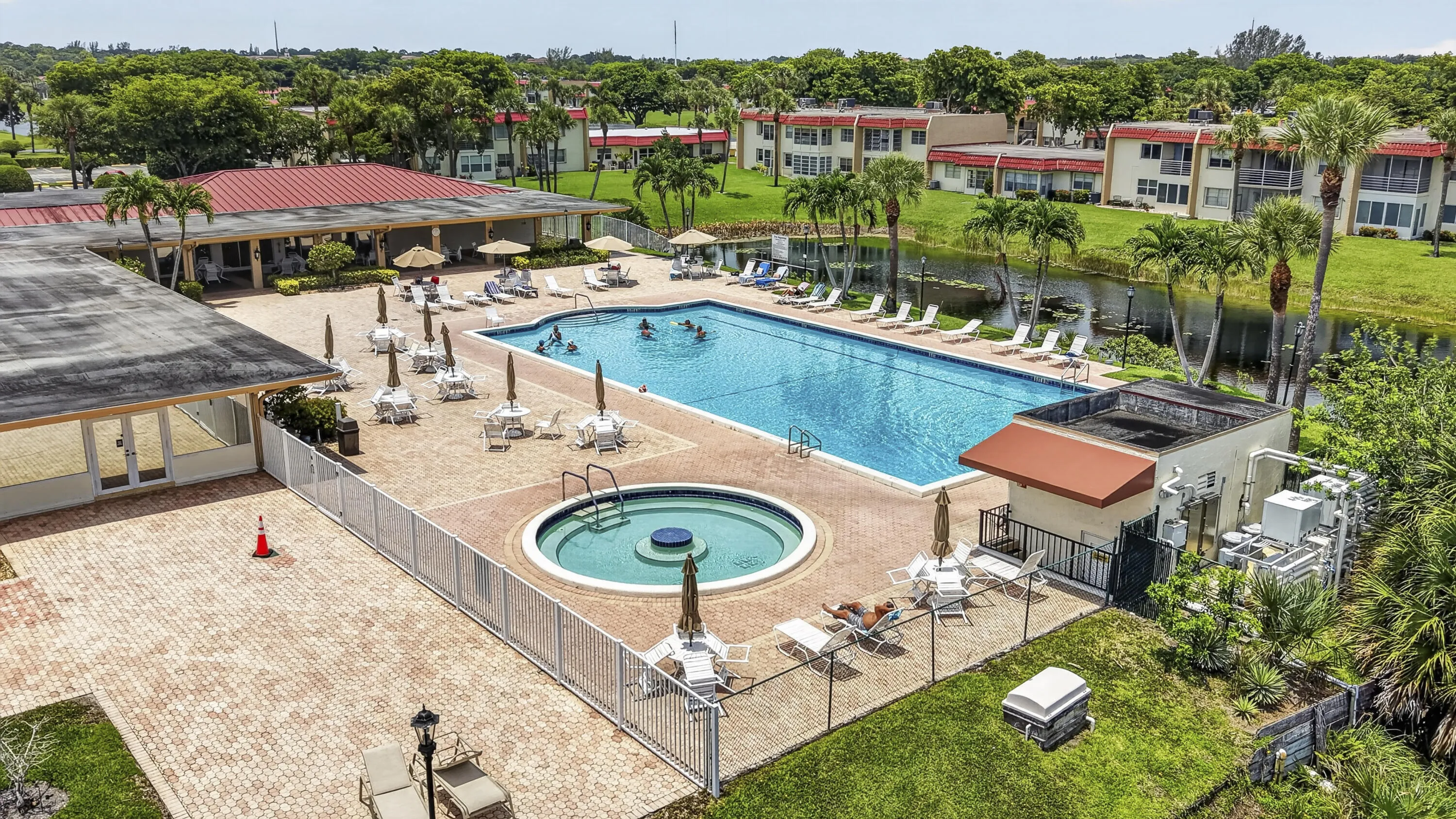 Community swimming pool with an adjacent spa, surrounded by a paver patio and ample lounge seating