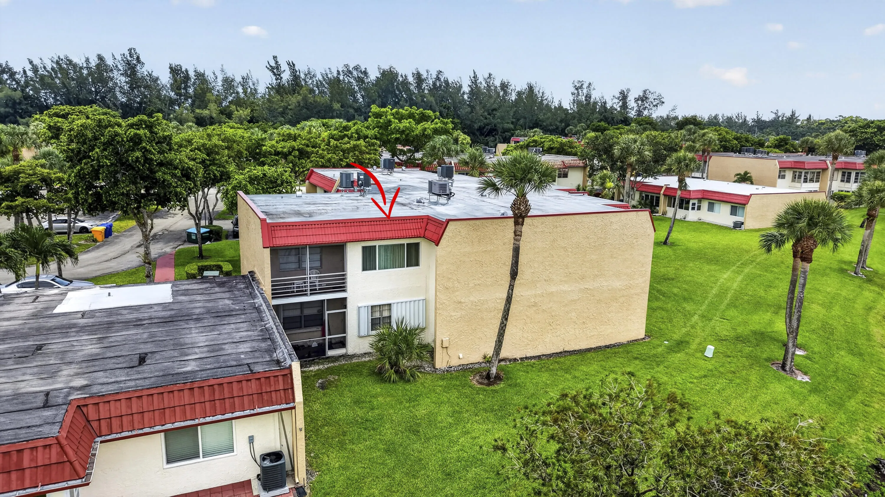 Two-story building featuring a red-trimmed flat roof and stucco exterior