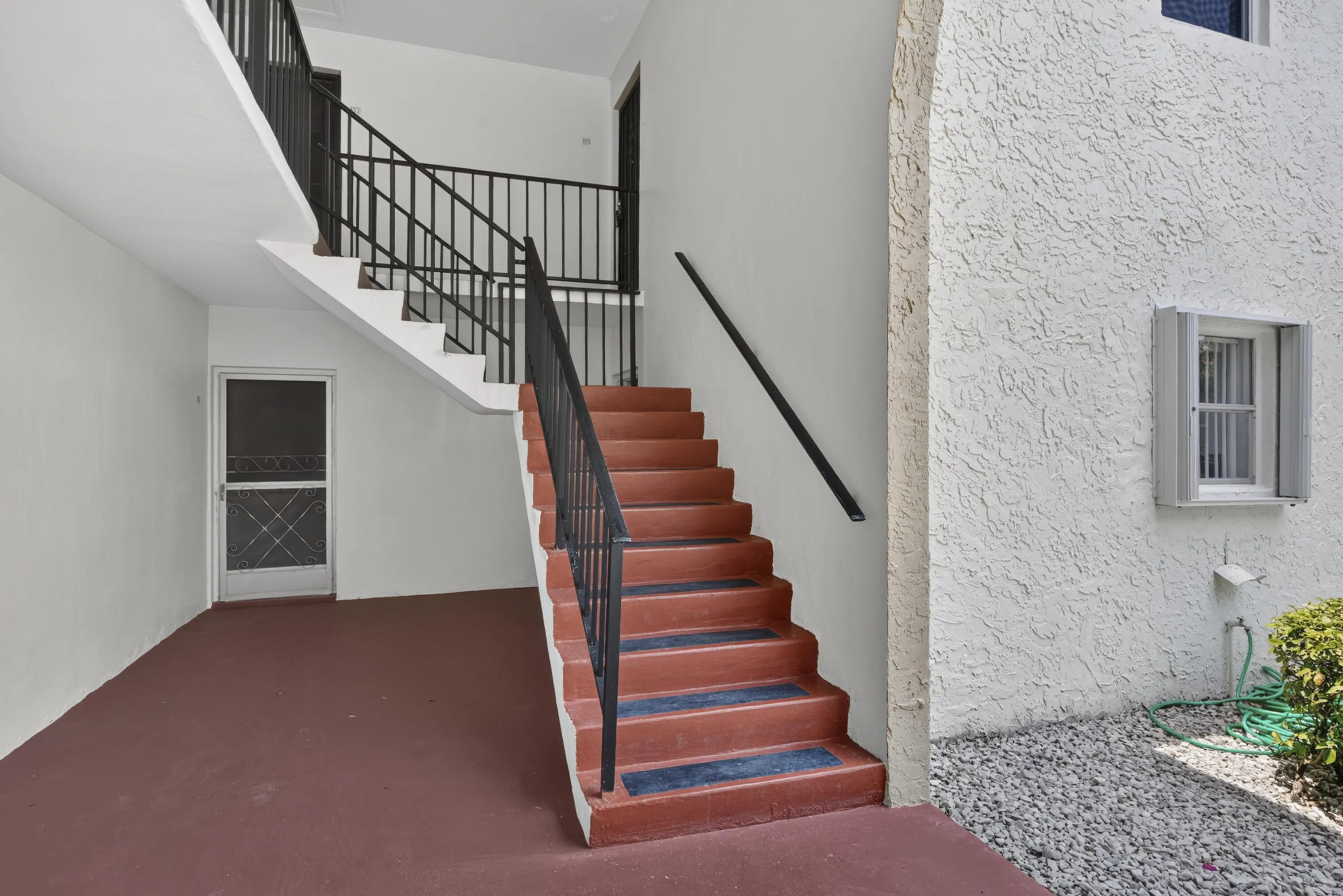 Exterior concrete staircase with black metal railings and a red-painted finish